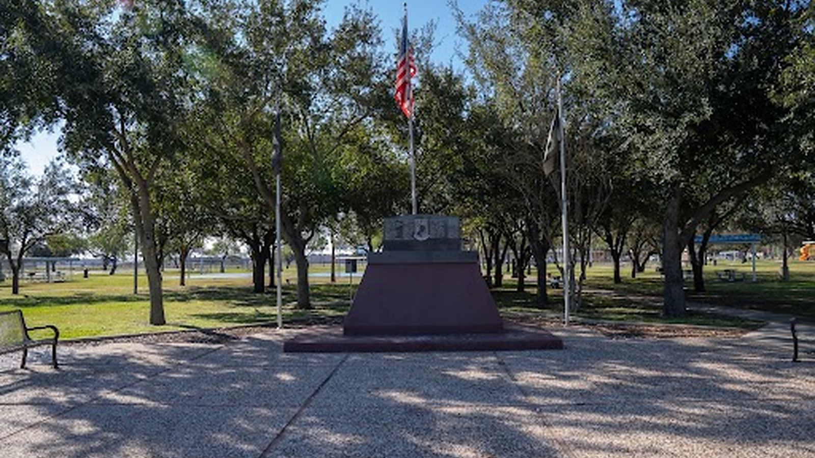 The veterans memorial and its flagpole under mature trees in a City of Edinburg park.