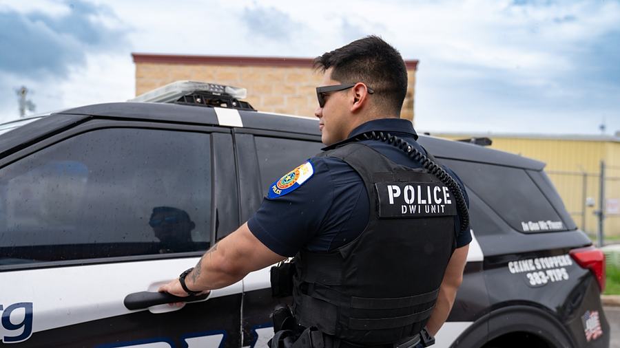 A City of Edinburg police officer at the open door of his unit.