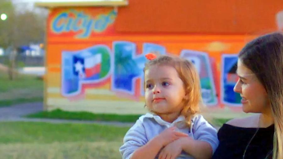 A mother and her small daughter in front of a painted City of Pharr mural.
