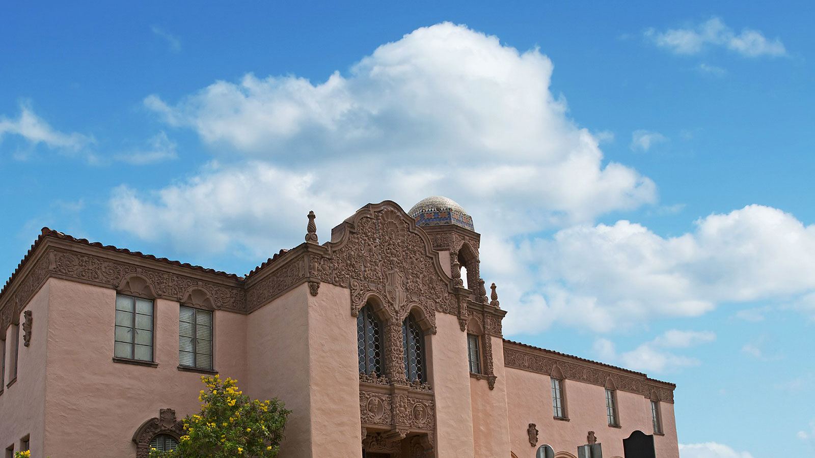 A historic Spanish Colonial Revival building in Weslaco — carved stonework, a tiled dome and a clay-tile roof against a clear sky. It is the architecture the city draws inside its own seal.